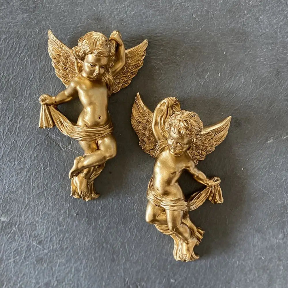 A pair of golden cherub angels wall decor set with wings and draped fabric.
