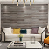 A modern living room featuring a gray wood grain accent wall, a white sofa, and a light-colored coffee table.