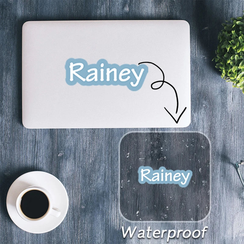A white laptop shows a name sticker being applied to the surface, with another waterproof sticker shown on a dark gray square
