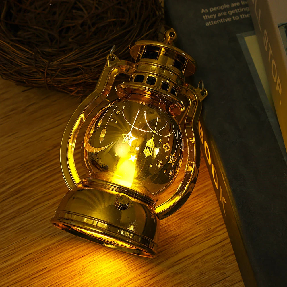 A golden LED lantern night light with a warm glow, featuring decorative stars and chains, resting on a wooden surface.
