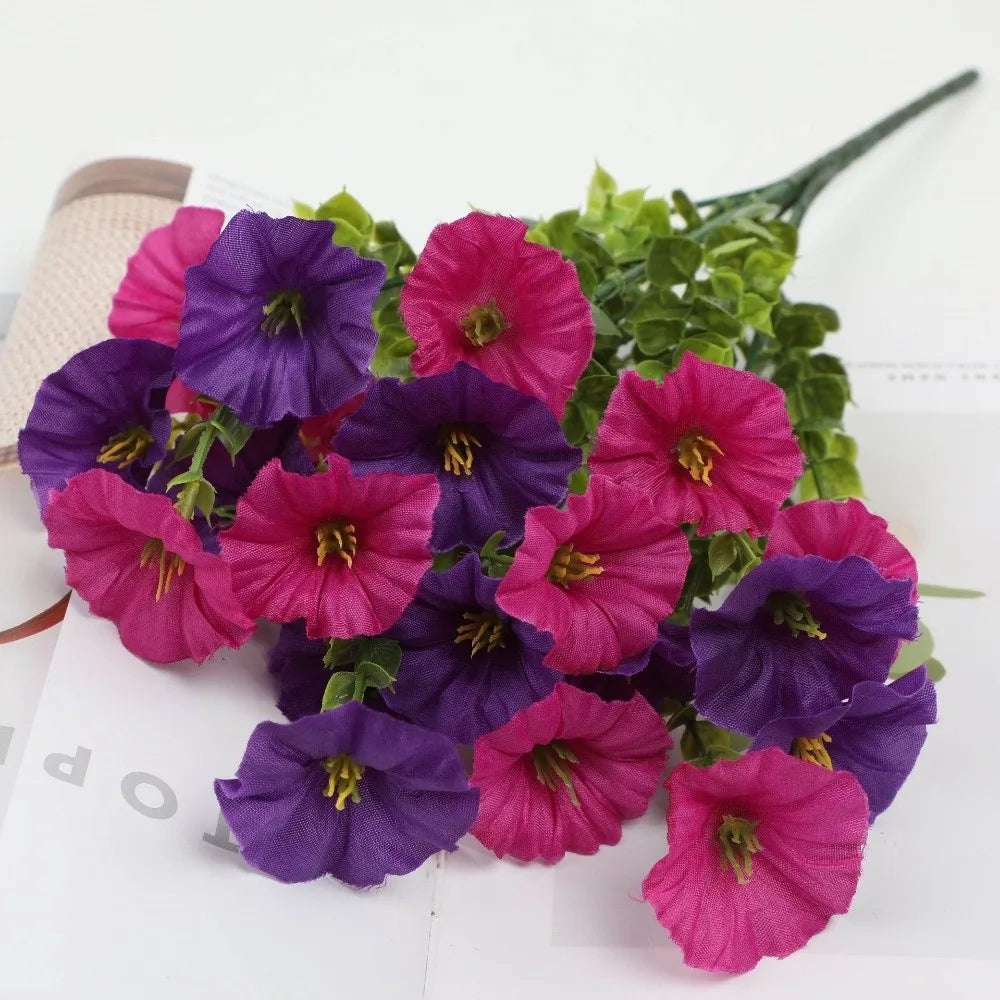 A bouquet of artificial pansy flowers in shades of purple and pink with green eucalyptus stems.