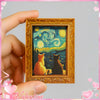 A framed print featuring a Van Gogh starry sky with two cats, held by a hand.