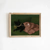 A framed canvas art print featuring a black cat sitting next to a gold-colored object on a green background.