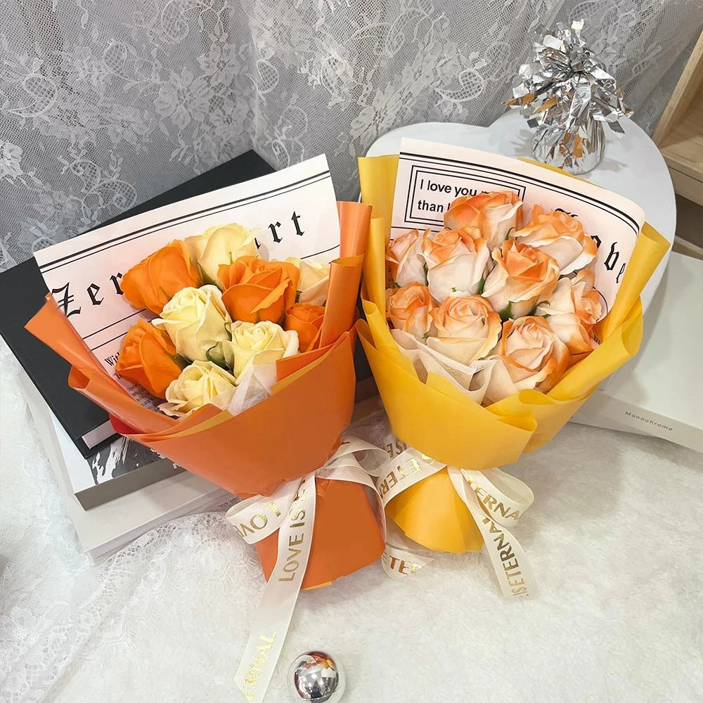 A bouquet of artificial orange and cream roses wrapped in yellow paper with a gold ribbon.