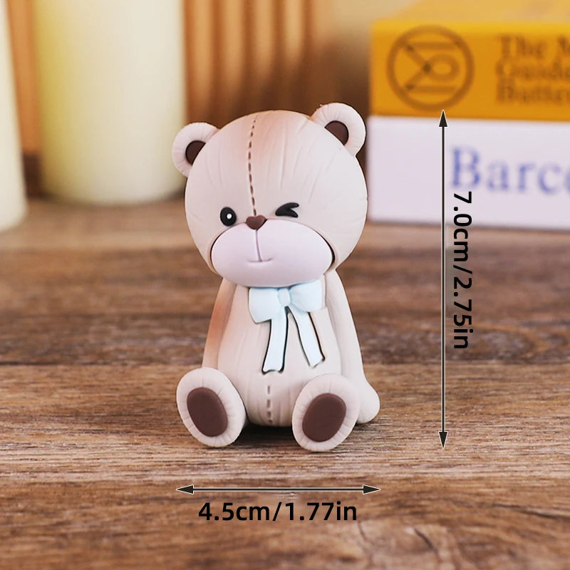 A light pink baby block cake topper featuring a bear design with a bow, shown against a wooden background.