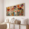A set of three framed floral canvas prints featuring colorful Scandinavian folk art designs on a white wall.
