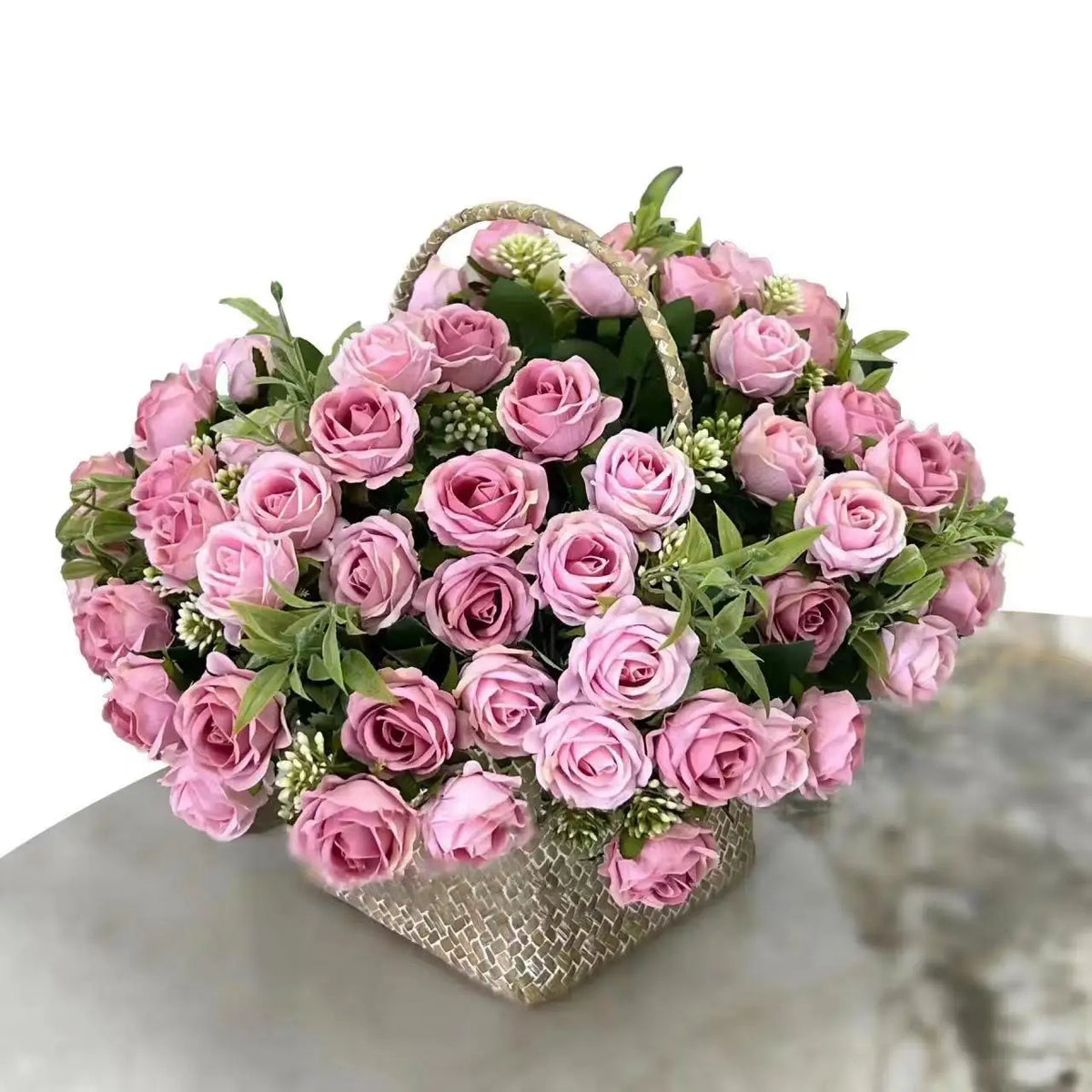 A bouquet of pink and mauve artificial roses in a woven basket for wedding decoration