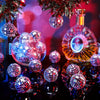 A close-up of a set of ten mirrored disco ball ornaments reflecting light on a dark surface.