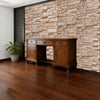 A dark wood antique cabinet sits against a textured stone wall in a room with a wooden floor.