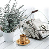 A potted artificial eucalyptus plant next to a gold cup on a white wooden surface.