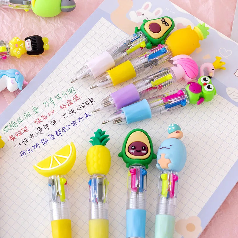 A set of five cute cartoon mini ballpoint pens in various bright colors and designs resting on a white grid paper.