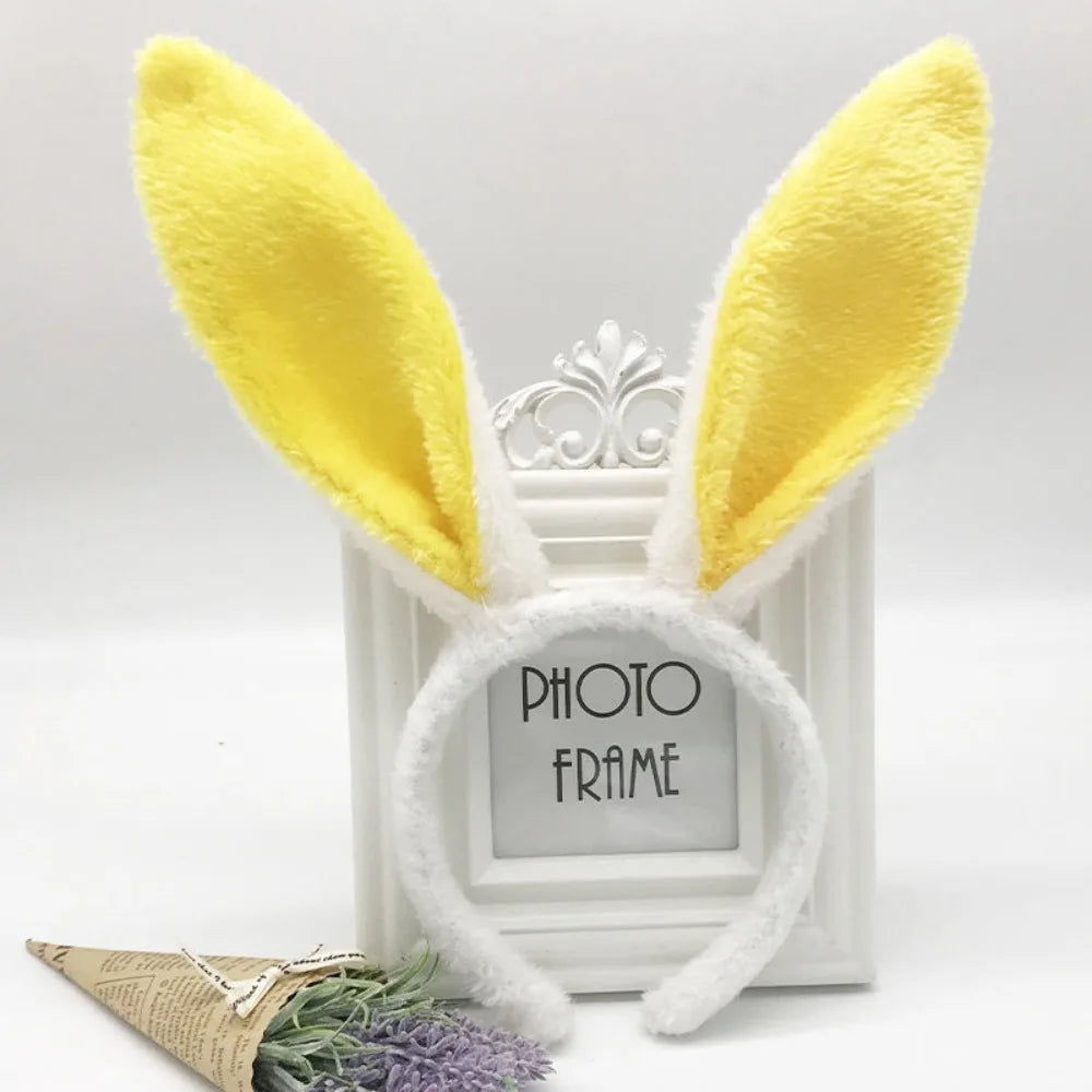 A pair of yellow bunny ears headband with a silver clip displayed in front of a white photo frame.
