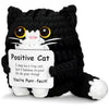A handmade black crochet cat doll with white fur and a positivity card.