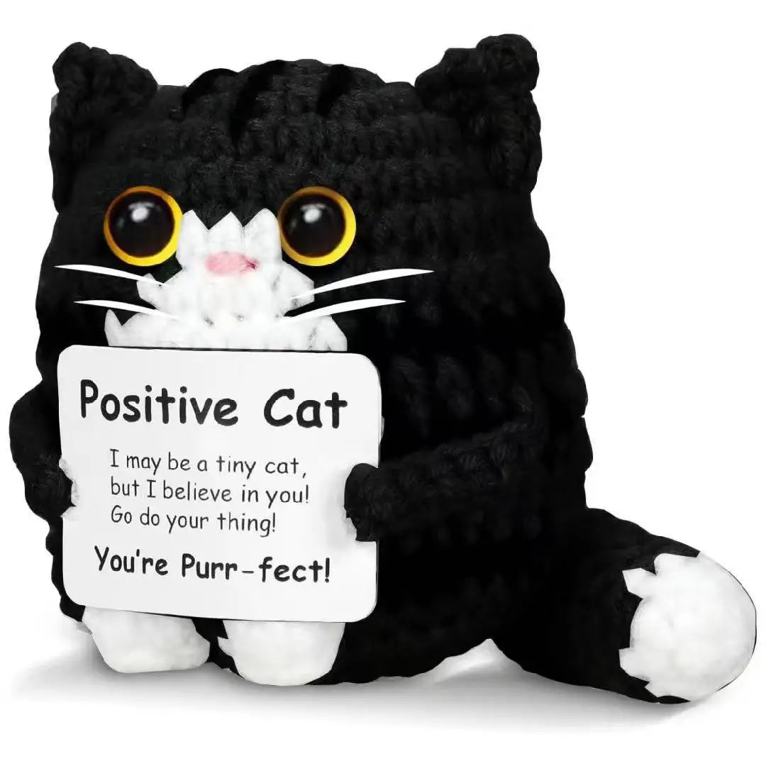 A handmade black crochet cat doll with white fur and a positivity card.