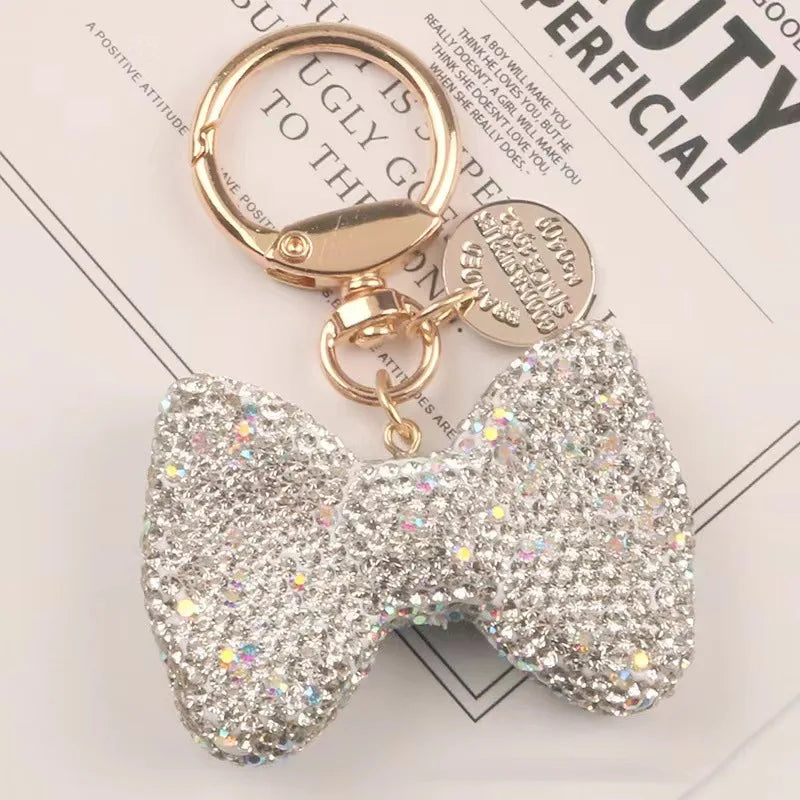 A sparkling rhinestone bow keychain with a gold-toned clasp and chain.