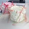 A white decorative fake cake with pink ribbons and flowers is displayed next to a pink cake.