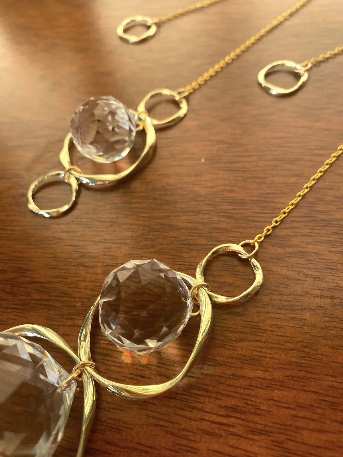 Bijoux de décoration en cristal ton or, avec des pierres facettées rondes sur des chaînes délicates.