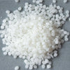 White microcrystalline wax pastilles for cosmetics scattered on a gray surface