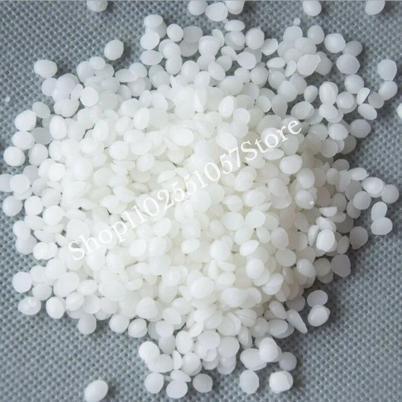 White microcrystalline wax pastilles for cosmetics scattered on a gray surface