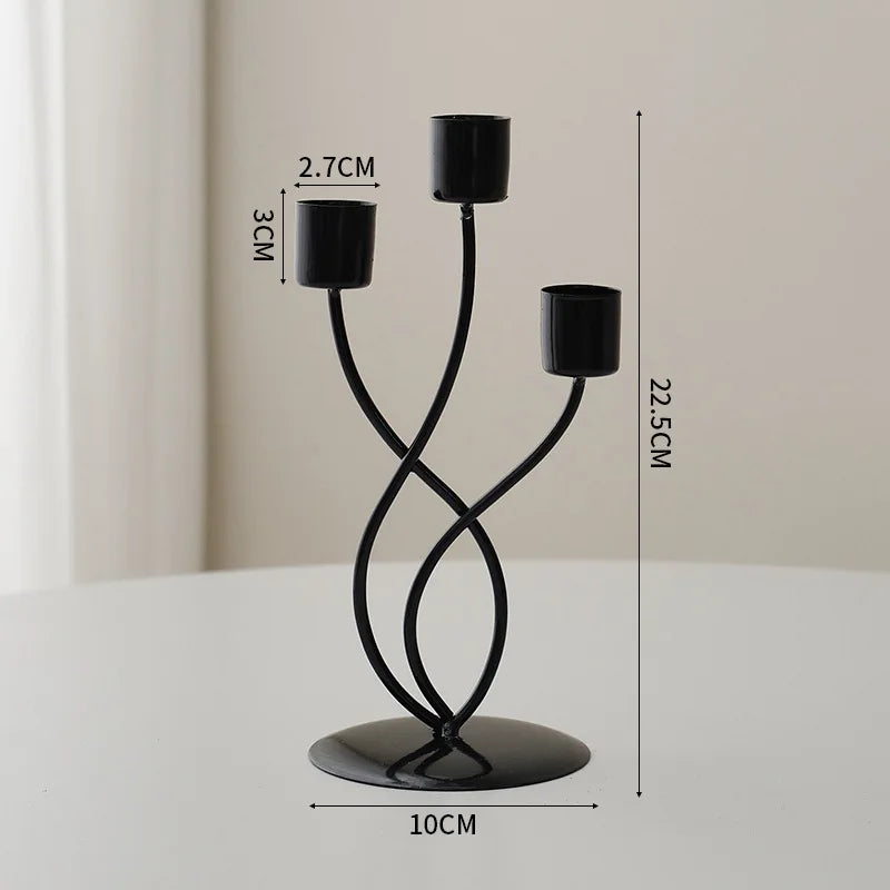 A black iron candle holder with three arms and a round base, shown against a white background.