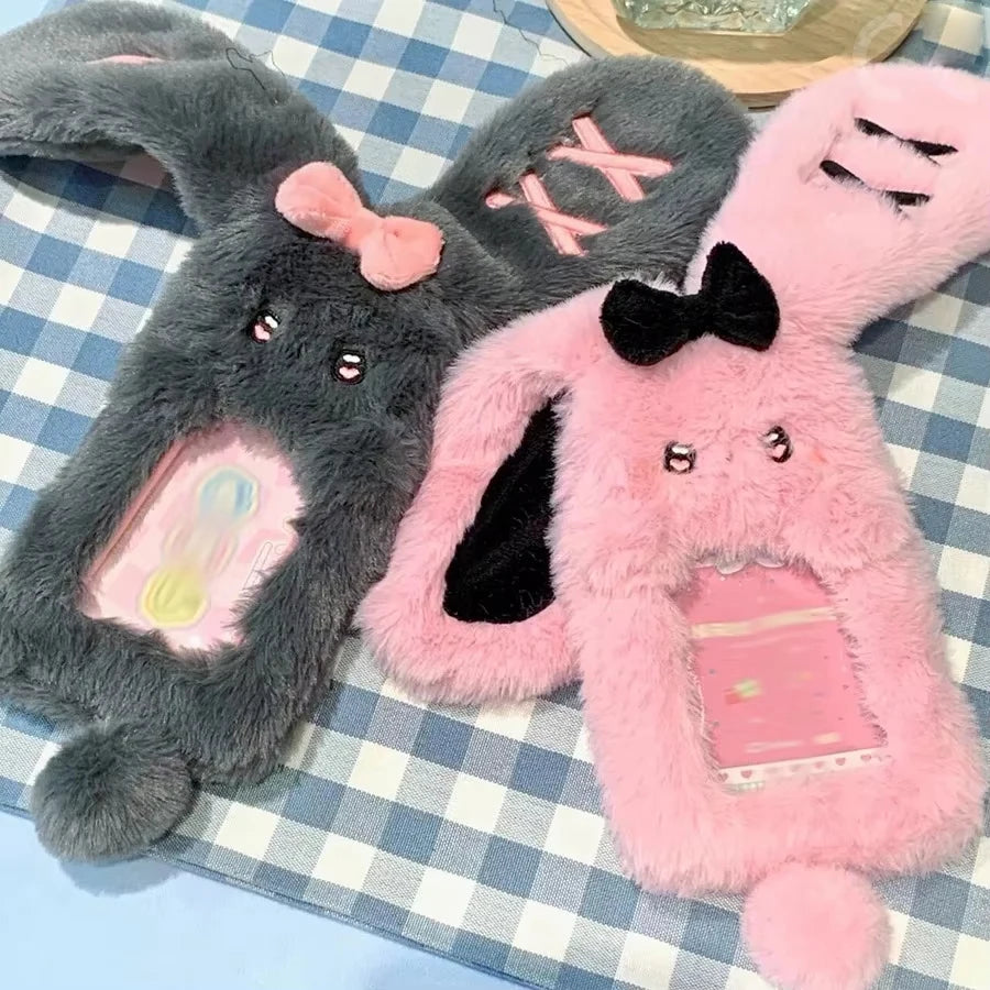 Ein Paar grauer und rosa Cartoon-Plush-Fotokarten-Halterungen liegt auf einem karierten Tuch.