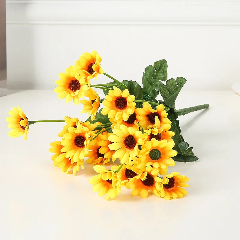 A bouquet of bright yellow artificial sunflowers with green leaves.