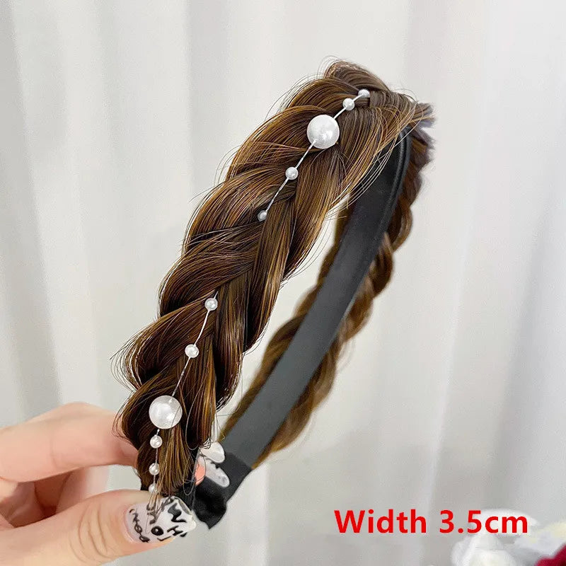 A close-up of a brown braided hair extension adorned with pearl and crystal hair bands.