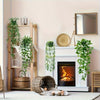 A display featuring artificial eucalyptus hanging vines in various sizes and a mirror on a white mantelpiece.