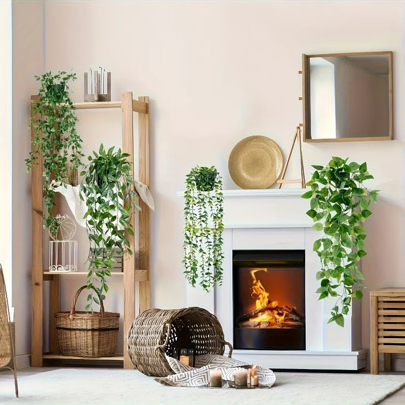 A display featuring artificial eucalyptus hanging vines in various sizes and a mirror on a white mantelpiece.