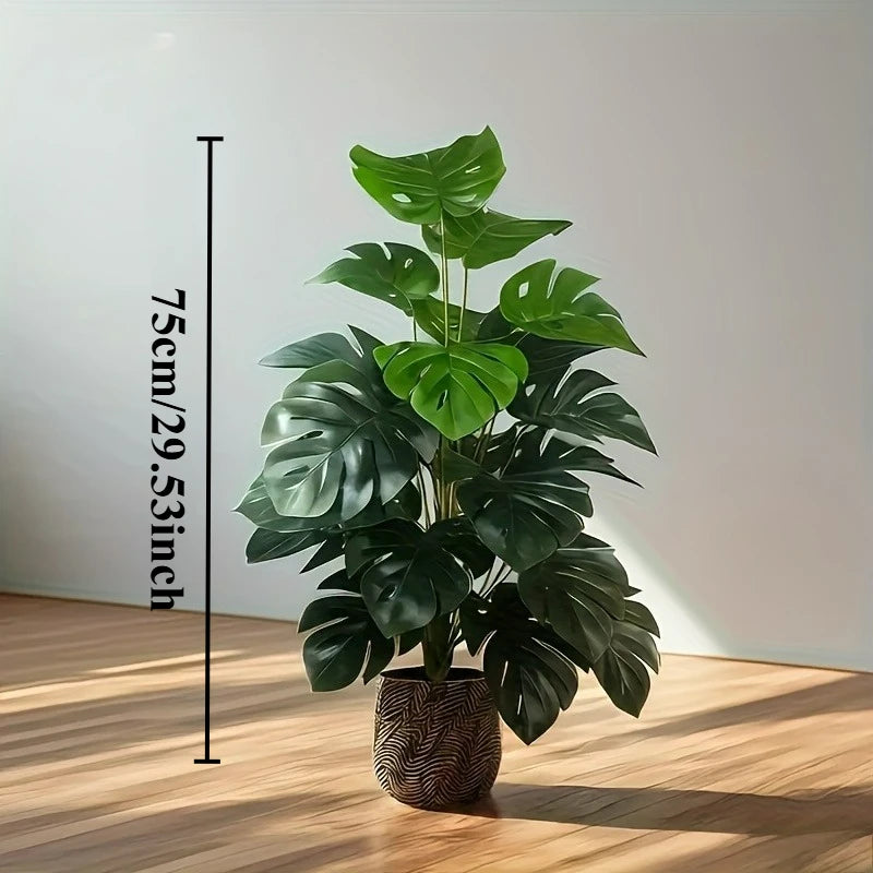 A lush green artificial monstera palm plant displayed in a pot against a white wall.
