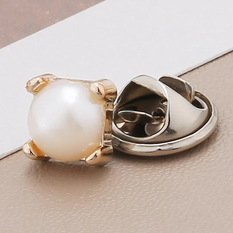 A close-up of a pearl and rhinestone no-sew brooch button, featuring a round white pearl set in gold-toned metal.