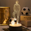 A glowing wireframe silhouette of a football stands on a dark base, illuminating a soccer ball in a dim setting.
