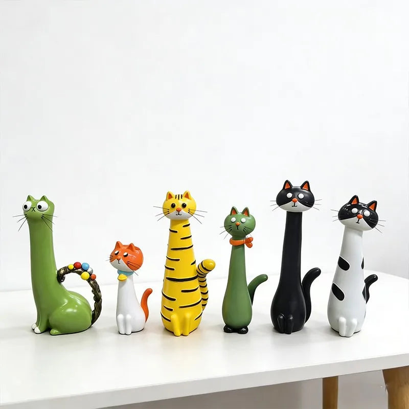A collection of seven cat-shaped resin figurines in various colors and poses displayed on a white surface.