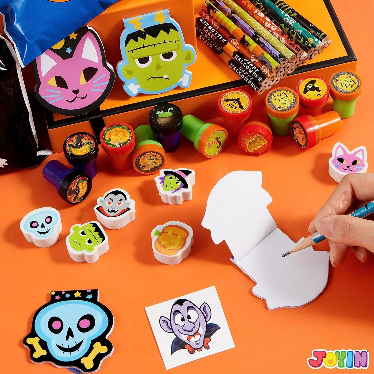 A collection of Halloween stationery items including masks, bags, and colorful markers and pencils.
