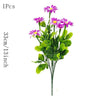 A bouquet of purple and pink silk daisies with green leaves.