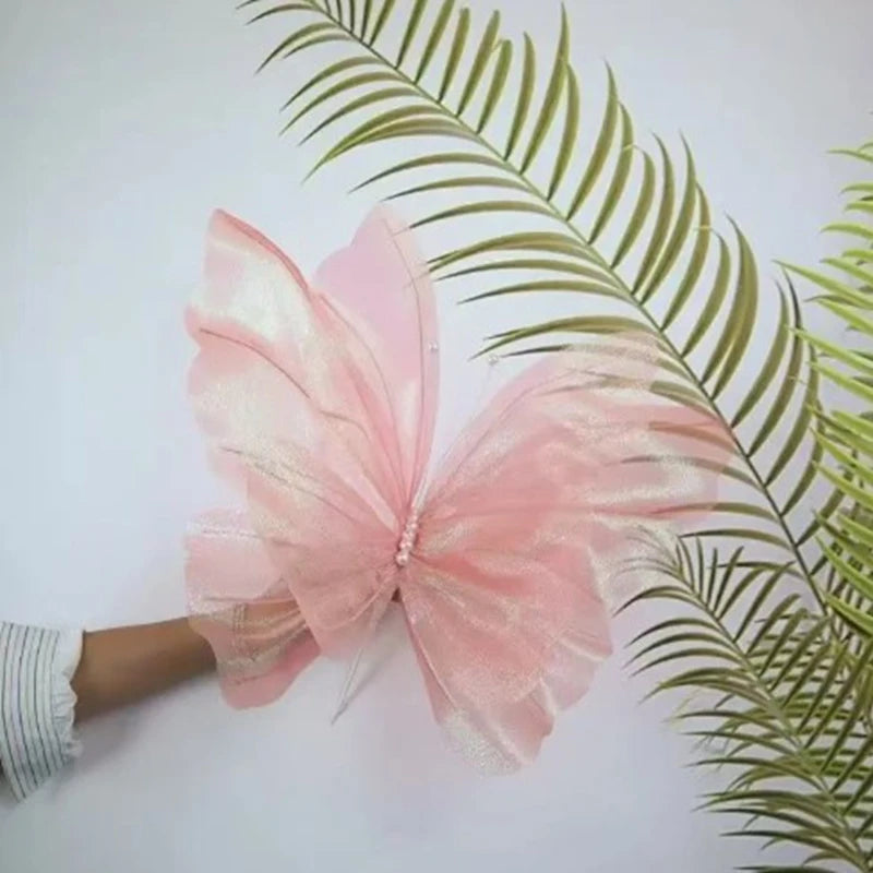 Pink silk artificial butterfly decoration resting on a green palm leaf.