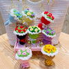A display of handmade crochet flower bouquets in various colors and textures, arranged on a pink wooden stand.