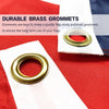 Close-up of a polished brass grommet on a white flag fabric against a red background.
