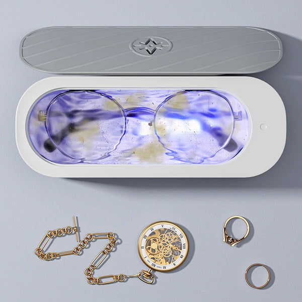Appareil ultrasonique pour nettoyer bijoux et verre avec chambre transparente, chaînes et bagues dorées.
