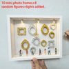 Weiße Präsentationsbox gefüllt mit goldenen und silbernen Fotorahmen, runden Silhouetten und Lichtern.