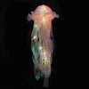 A glowing jellyfish lantern lamp with translucent pink and green fibers suspended against a black background.