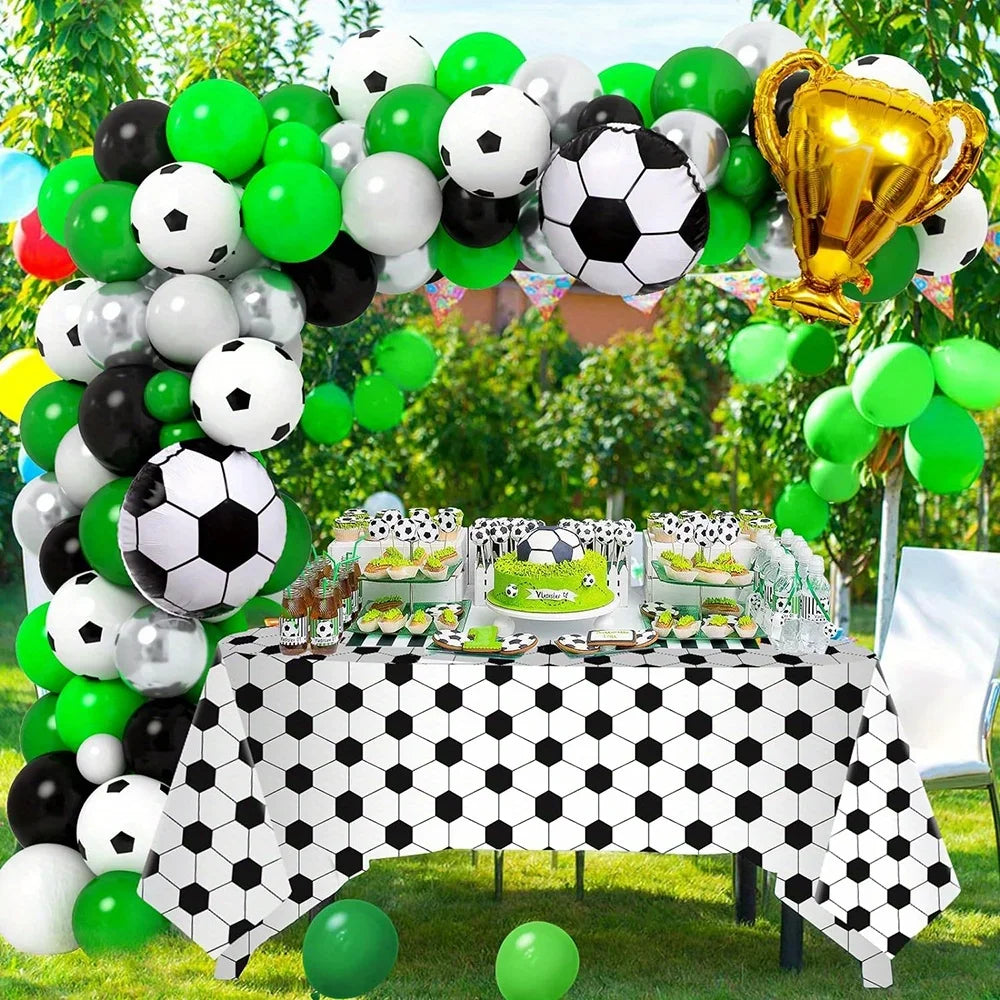 A balloon arch display featuring black, white, and lime green soccer balls for a football-themed party.