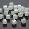 A collection of square cut glass crystal beads in white and clear colors displayed on a dark surface.