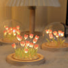 A small glass terrarium filled with glowing LED tulips used as a decorative night light.