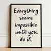A framed canvas print with black script text on a light background that reads Everything seems impossible until you do it.