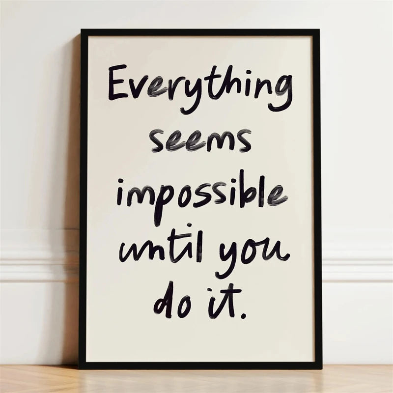 A framed canvas print with black script text on a light background that reads Everything seems impossible until you do it.
