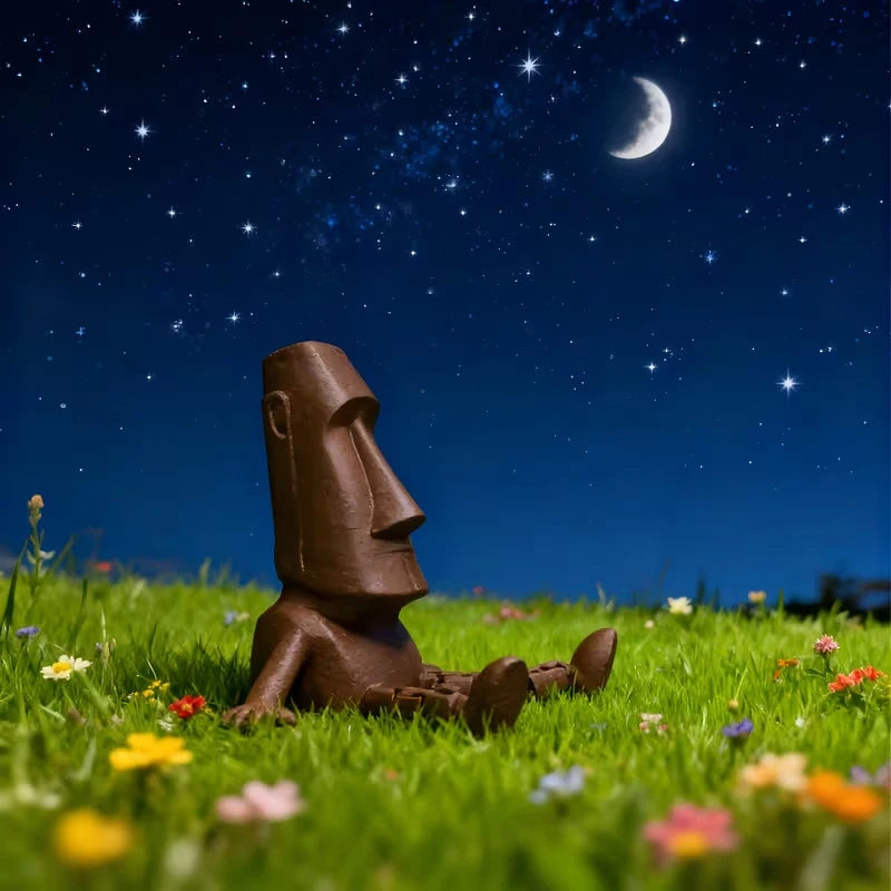 A 3D printed Moai statue figurine with movable joints resting in a grassy field under a starry night sky.
