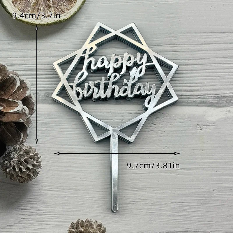 A silver acrylic birthday cake topper with the words Happy Birthday on a stick, placed next to a slice of citrus fruit.