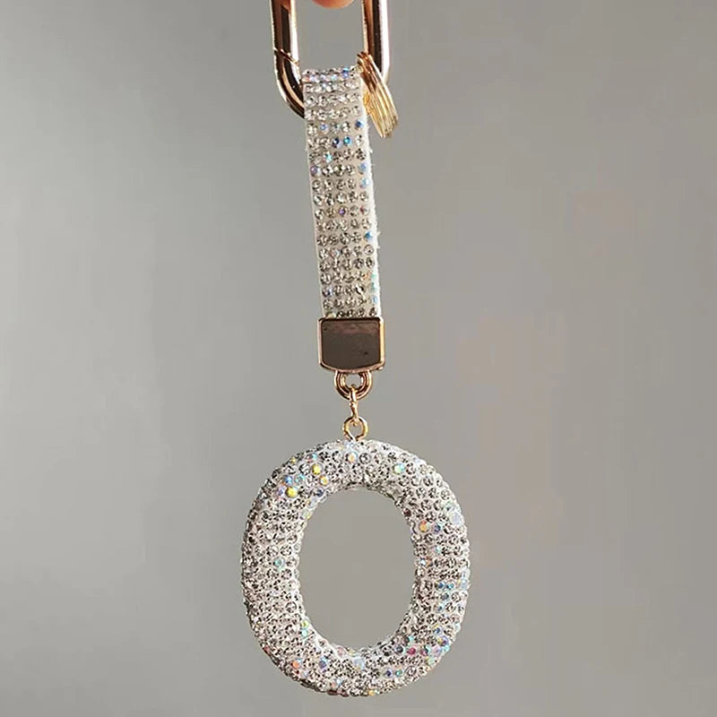 A sparkling crystal letter keychain charm hanging from a gold-toned clasp.