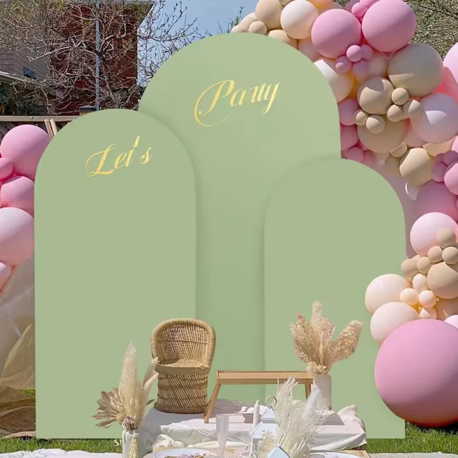 A pastel pink and cream balloon arch backdrop featuring green arched signs for a party event.